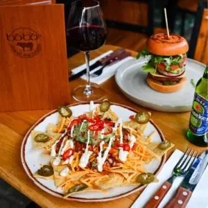 Restaurant table with a burger, loaded fries and a glass of red wine